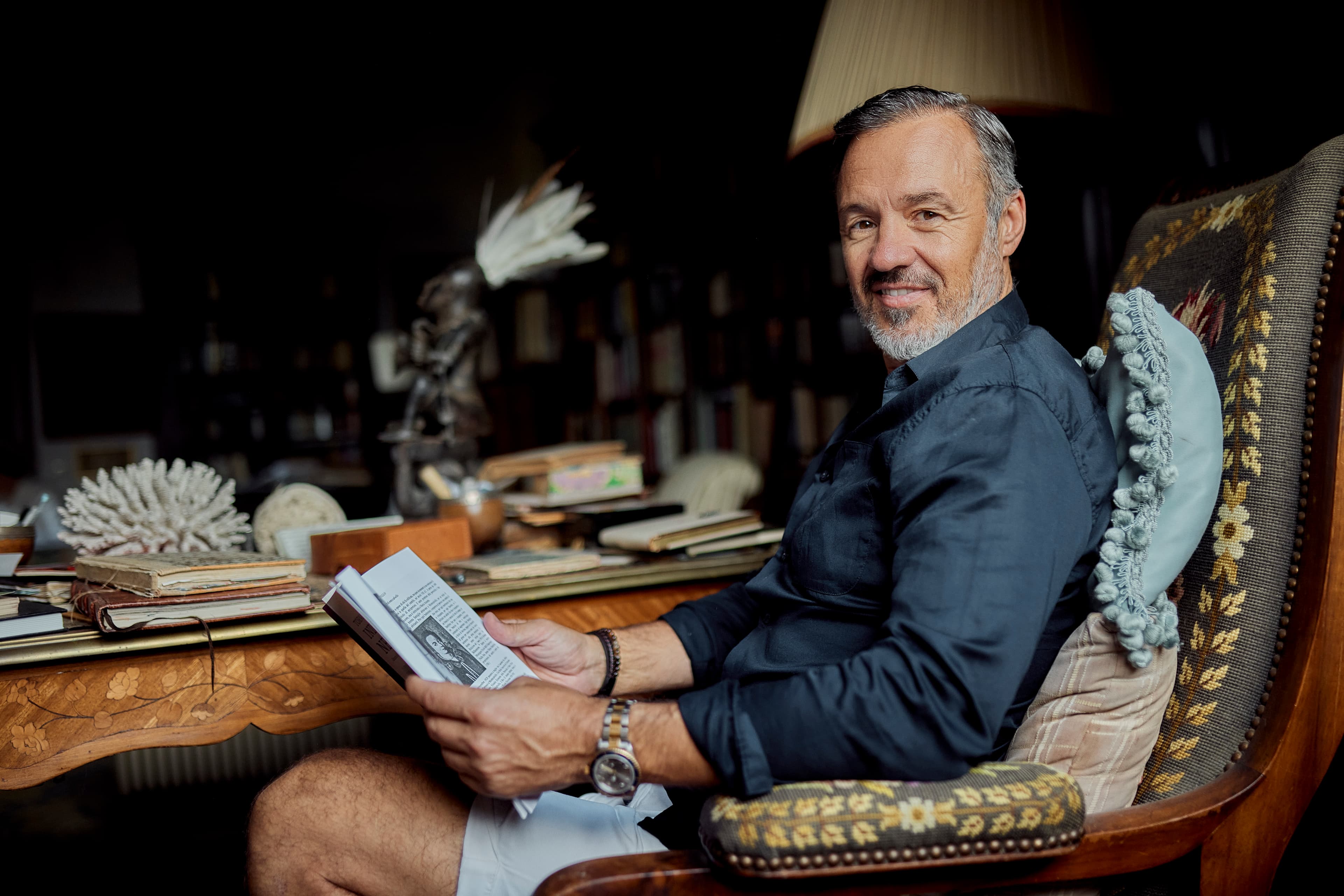Eric Edmeades in library armchair holding book